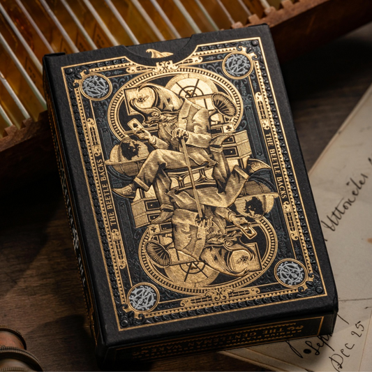 Decorative book with intricate gold designs on a wooden surface with vintage items. Beetle Backs Prestige Edition Playing Cards