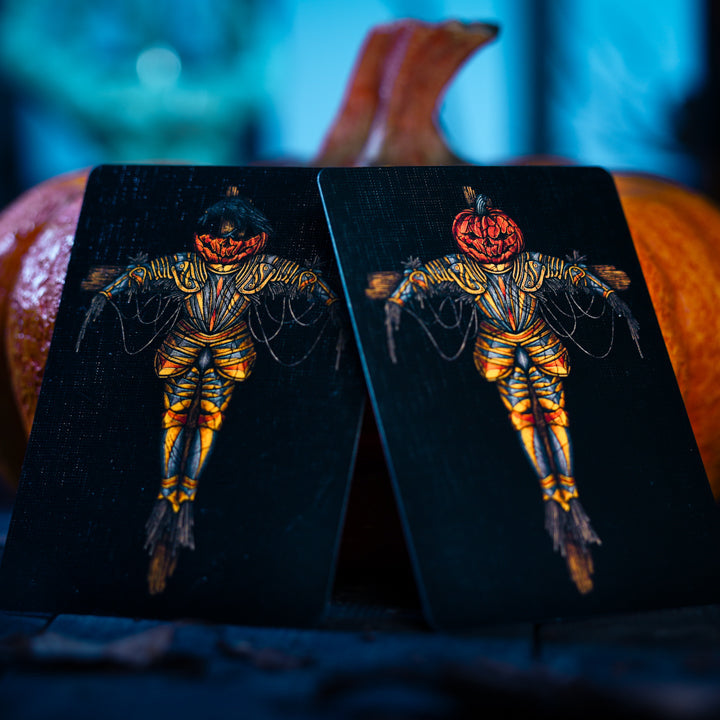 Two Halloween-themed playing cards with skeletons and pumpkins on a dark background.