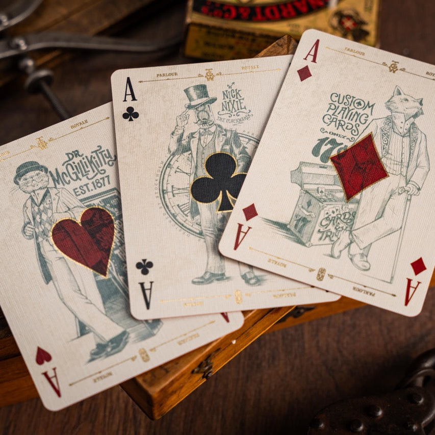 Four playing cards with unique designs on a wooden surface