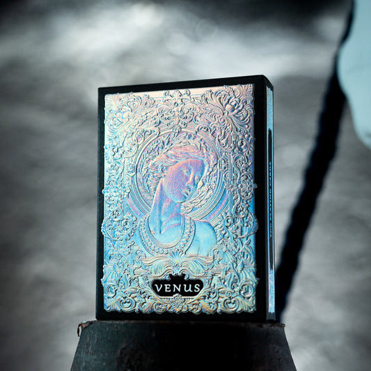 Decorative box with embossed design and 'Venus' branding, surrounded by classical sculptures.