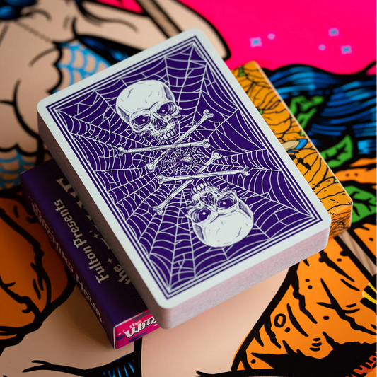 Playing card with skull and spider design held over a colorful background