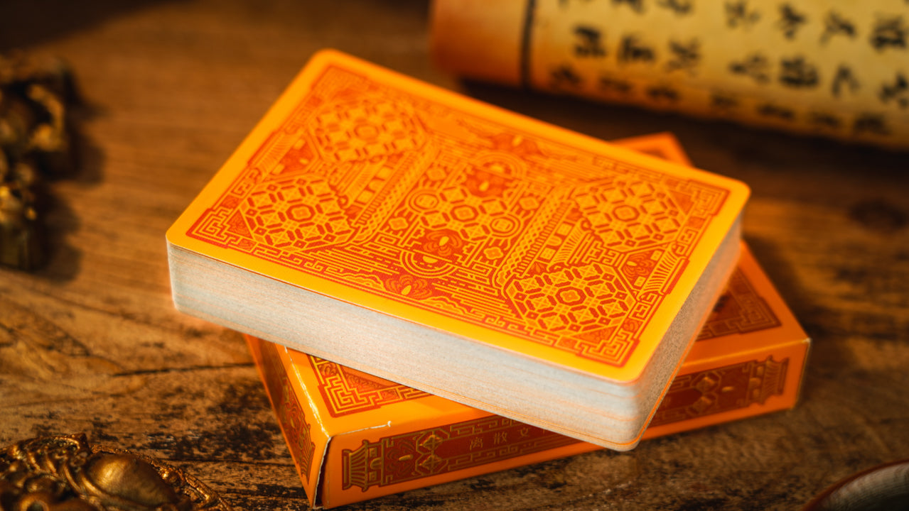 Stack of orange playing cards on a wooden surface with traditional Chinese elements.