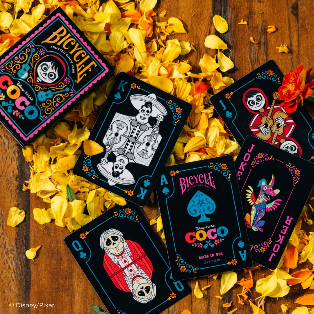 Bicycle Coco playing cards on a wooden surface with yellow petals