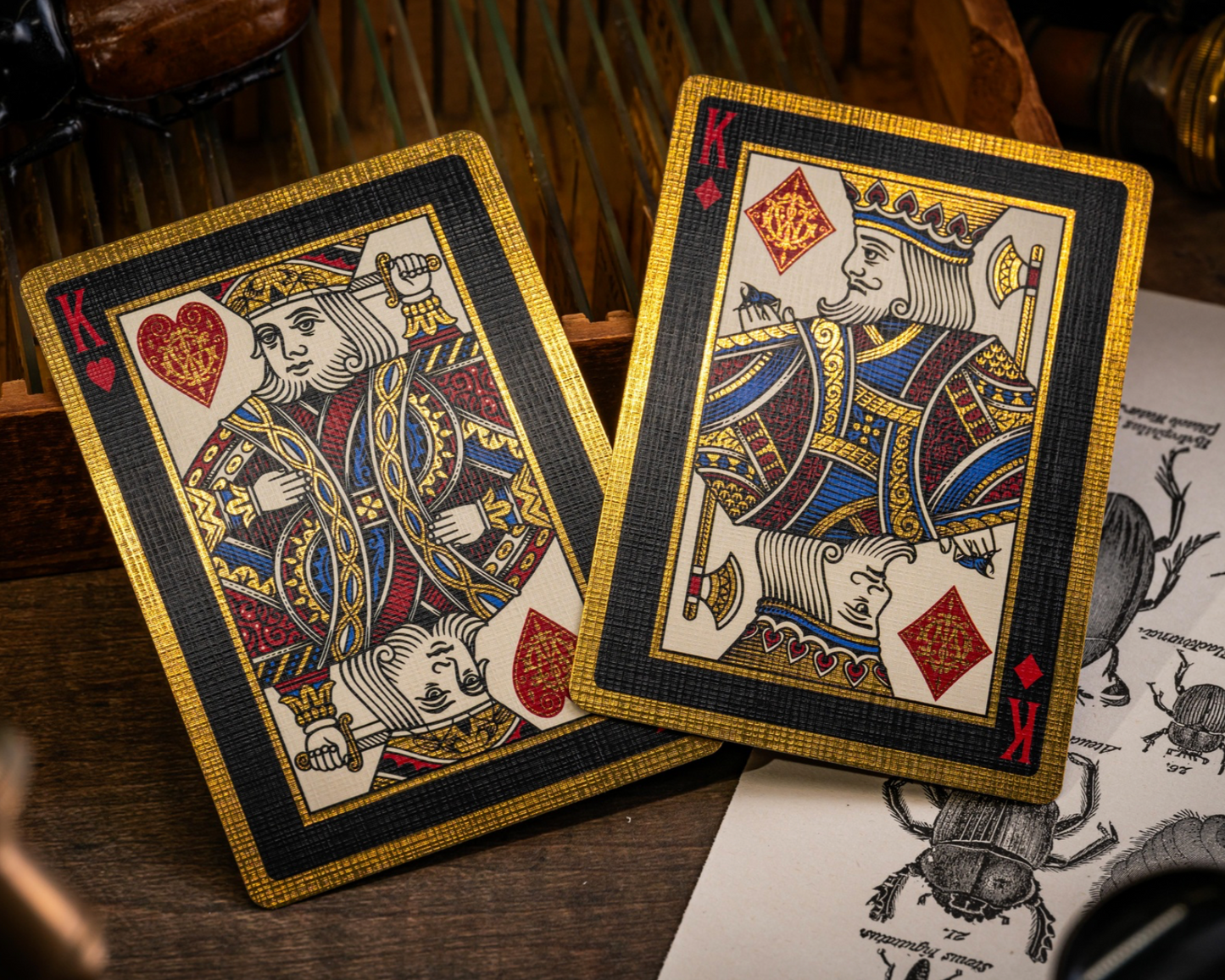 Two playing cards, the King of Hearts and the King of Spades, on a wooden surface with a detailed card design.