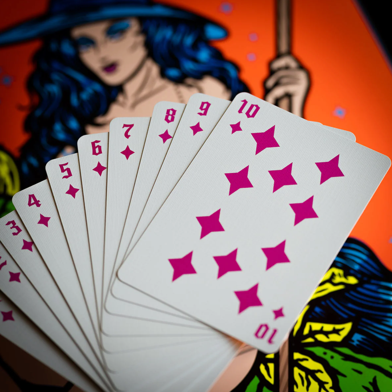 Playing cards with star design held by a person against a colorful background