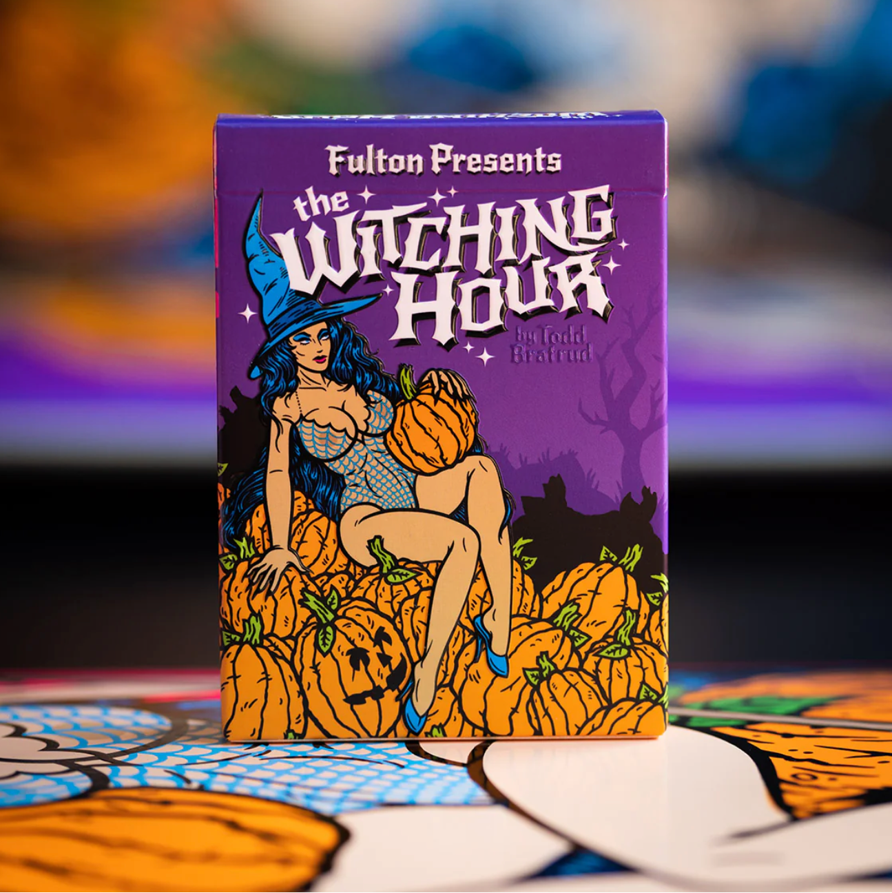 Playing card deck packaging titled 'The Witching Hour' with a witch and pumpkins design on a purple background.