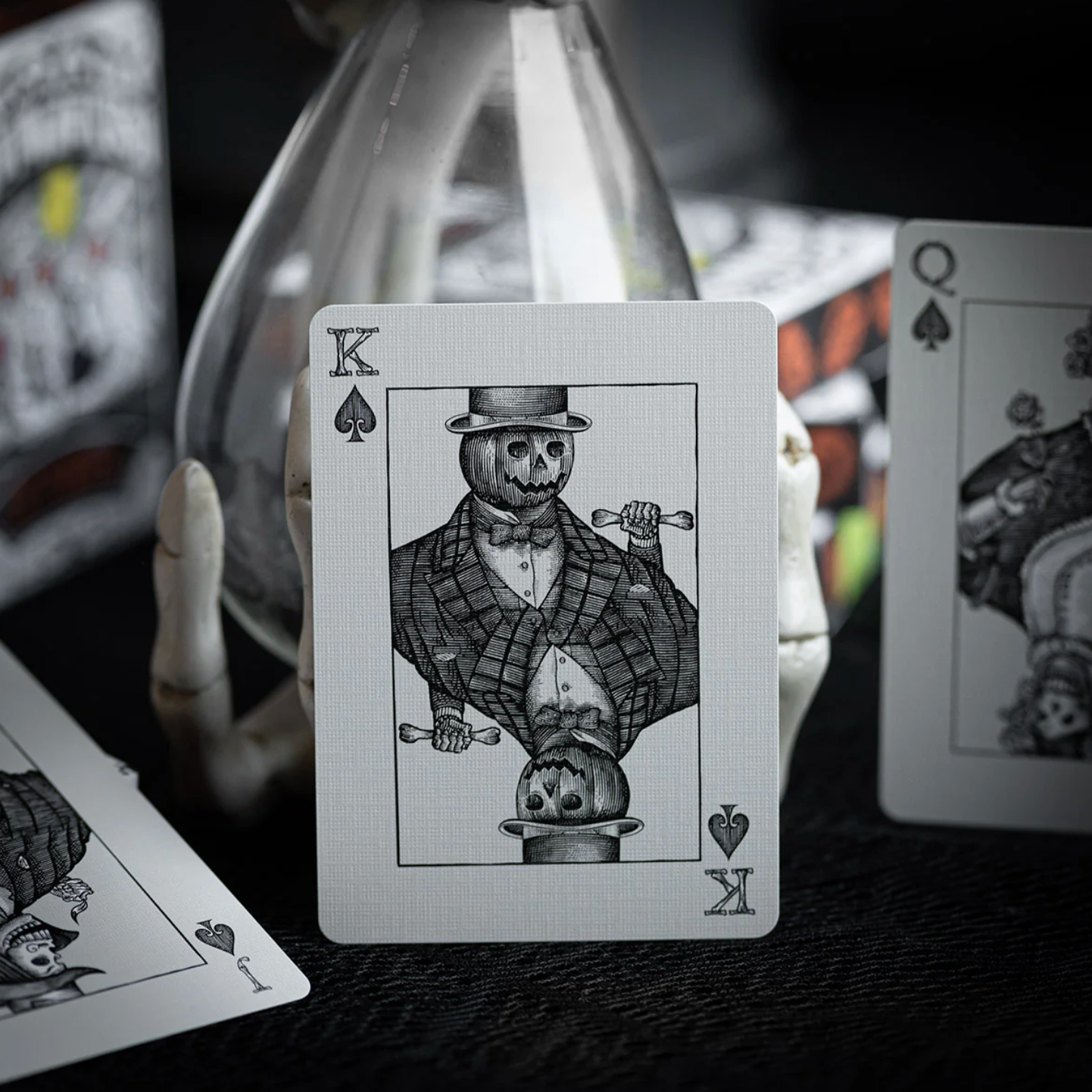 Playing card with a skeleton in a top hat and suit, surrounded by other playing cards.