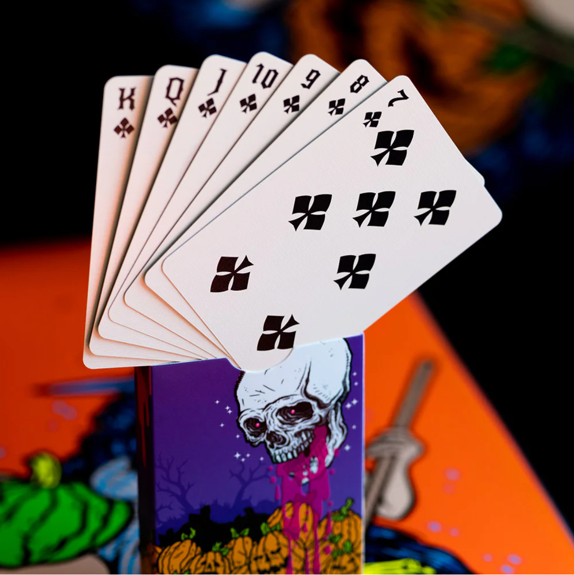 Playing cards with a skull design on a Halloween-themed card in the background