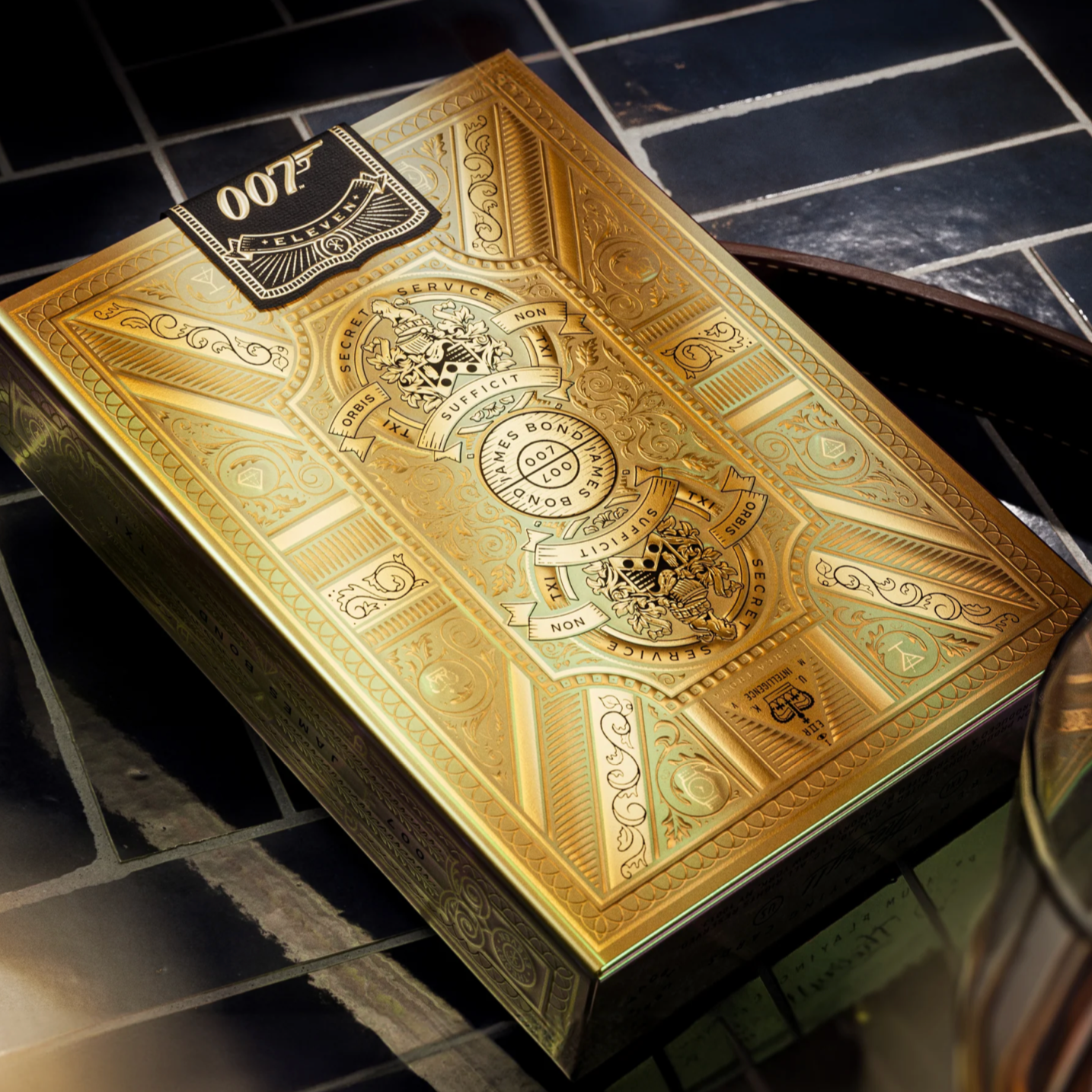 Gold playing card box with intricate designs on a reflective surface