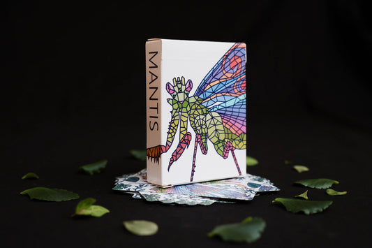 Mosaic Mantis Playing Cards housed in a white tuck box with a colorful stained-glass-style mantis illustration and the word "MANTIS" printed vertically on the side of the box.
