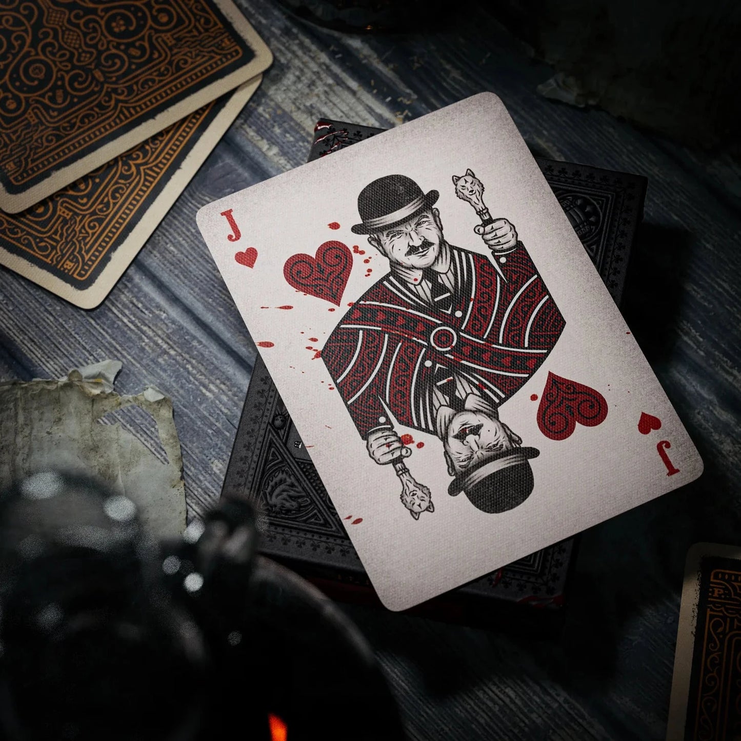 Playing card with a design of a man holding a heart and a sword on a wooden surface.