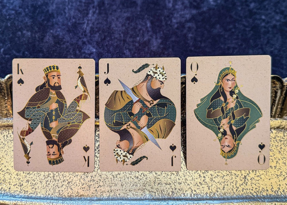 Three playing cards featuring stylized figures on a decorative stand with a blue background