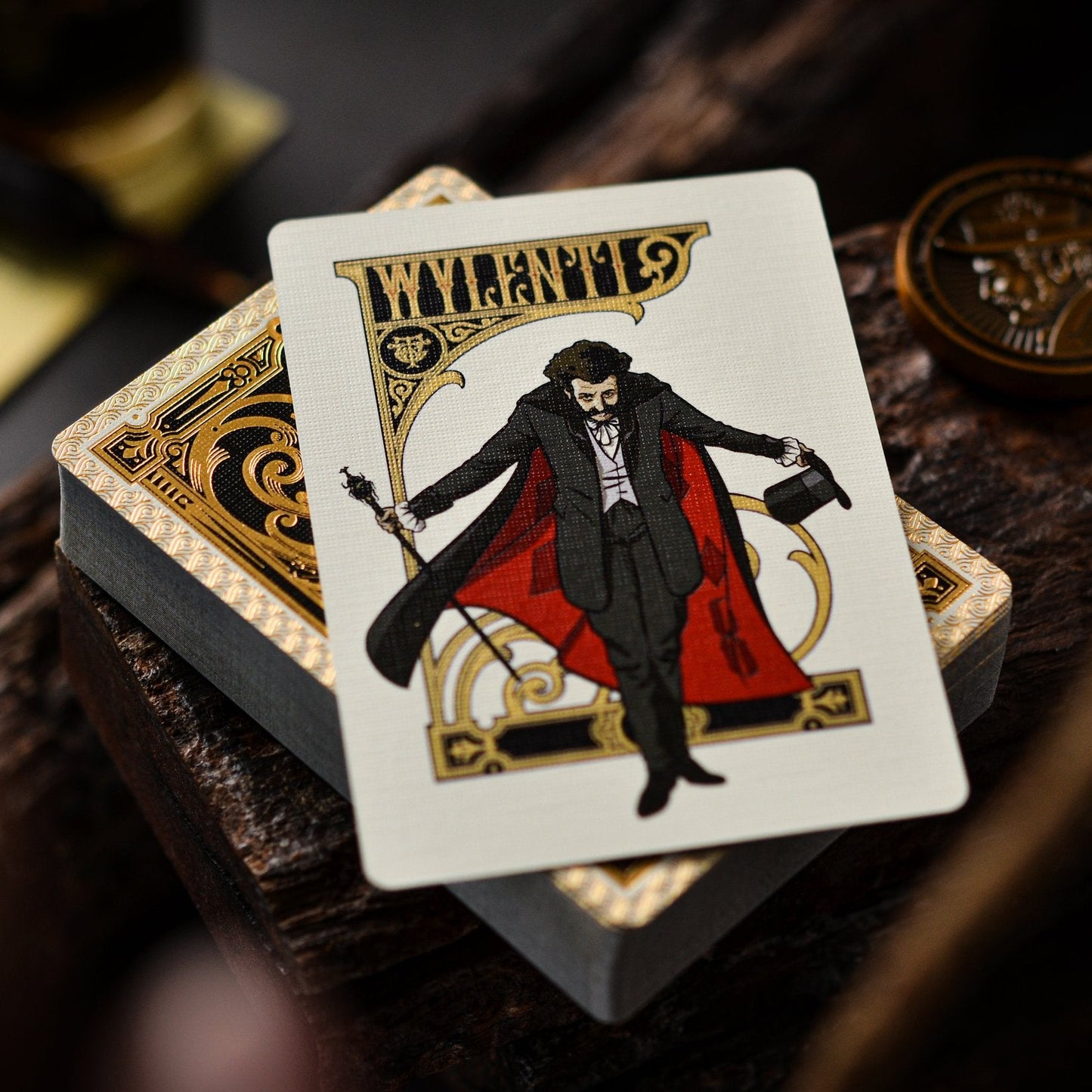 Playing card with a character in a red cape and black coat on a wooden surface.