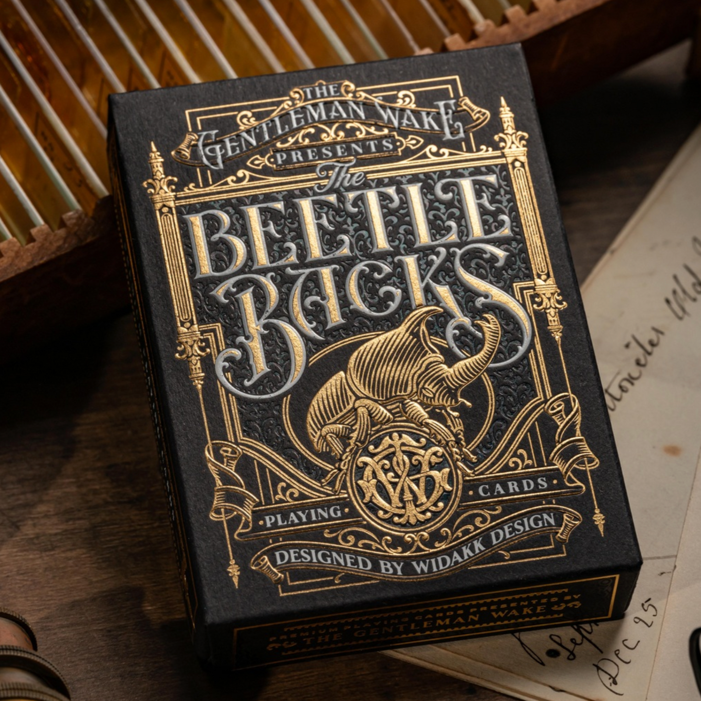 Beetle Backs Prestige Edition Playing card box with ornate design and text on a wooden surface