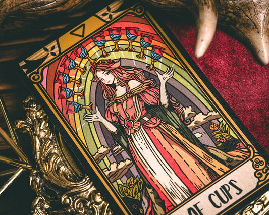 Tarot card featuring a woman with red hair and a rainbow-colored background, placed on a textured surface.